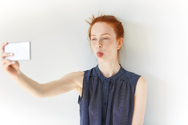 Ritratto di giovane donna dai capelli rossi che cattura selfie