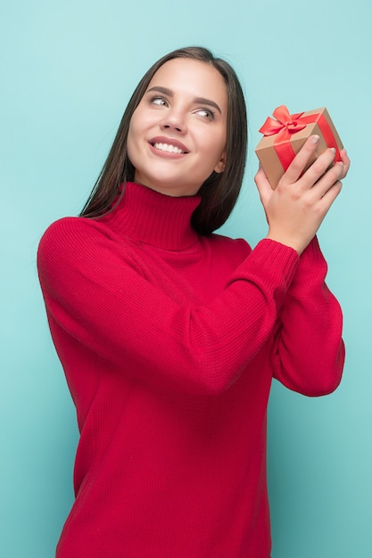 Ritratto di giovane donna felice che tiene un regalo isolato su blue