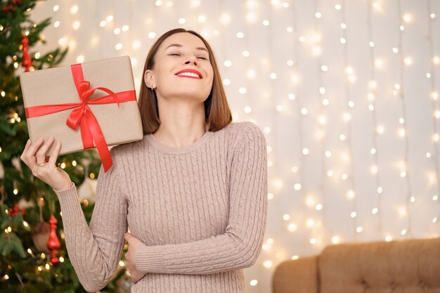 Ritratto di giovane donna felice labbra rosse che guarda l'obbiettivo che tiene una confezione regalo avvolta