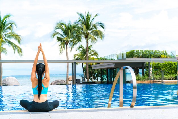 Ritratto di giovane donna (fitness, yoga, perfetto abbronzato, pelle sana) in piscina di lusso. Viaggi e Vacanza. Concetto di libertà. Colpo all&#39;aperto