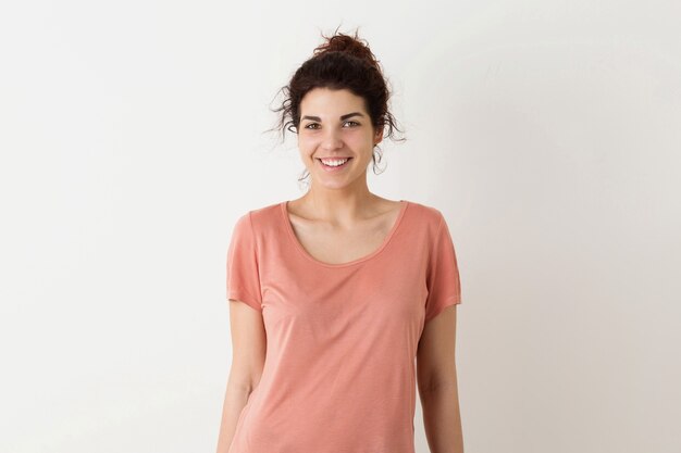 Ritratto di giovane donna graziosa dei pantaloni a vita bassa felice sorridente sembrante naturale in posa rosa della camicia isolata sul fondo bianco dello studio