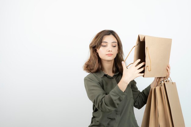 Ritratto di giovane donna in possesso di sacchetti di carta artigianale e in piedi. Foto di alta qualità