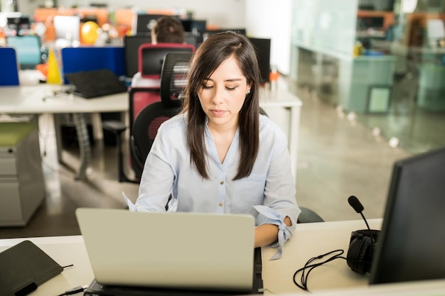 Ritratto di giovane donna latina in casual che lavora al computer portatile