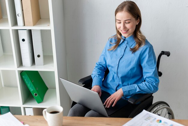 Ritratto di giovane donna positiva che lavora ad un computer portatile