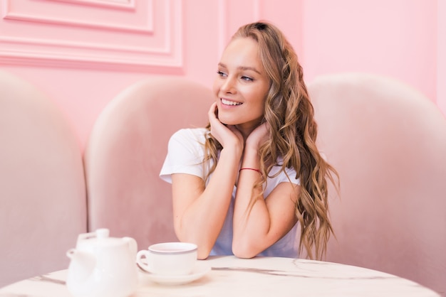 Ritratto di giovane donna splendida bere il tè nella moderna caffetteria durante la sua pausa di lavoro