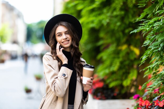 Ritratto di giovane donna urbana che cammina e che parla sul telefono cellulare sulla strada