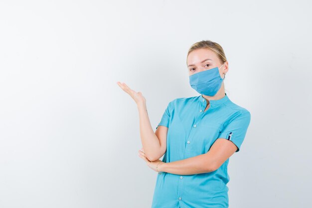 Ritratto di giovane dottoressa che tiene qualcosa in uniforme isolata