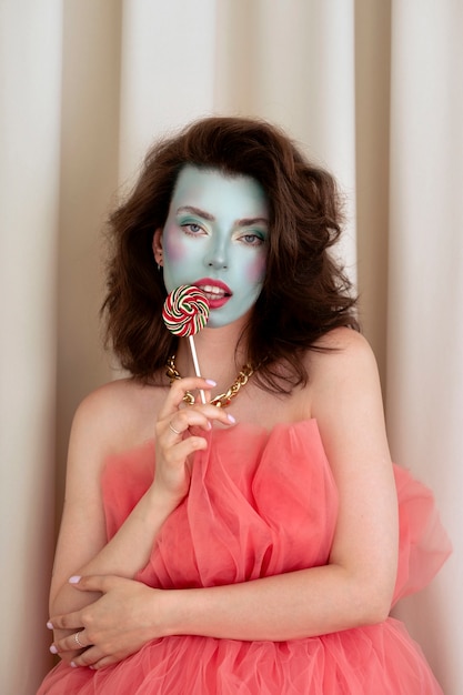 Ritratto di giovane e bella donna con trucco viso colorato e lecca-lecca