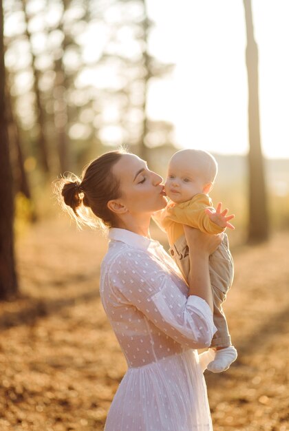 Ritratto di giovane famiglia attraente con figlio piccolo bambino, in posa nella bellissima pineta autunno al giorno pieno di sole. Bell'uomo e la sua bella mora moglie