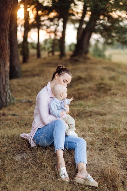 Ritratto di giovane famiglia attraente con figlio piccolo bambino, in posa nella bellissima pineta autunno al giorno pieno di sole. Bell'uomo e la sua bella mora moglie