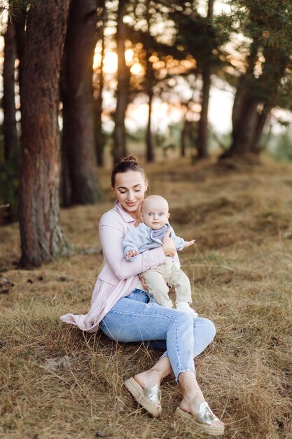 Ritratto di giovane famiglia attraente con figlio piccolo bambino, in posa nella bellissima pineta autunno al giorno pieno di sole. Bell'uomo e la sua bella mora moglie