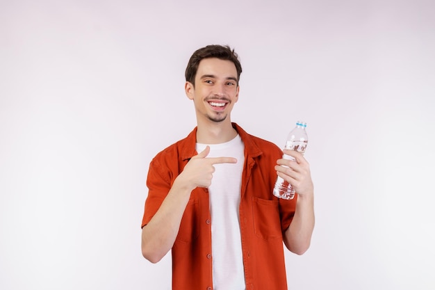 Ritratto di giovane felice che mostra l'acqua in una bottiglia isolata su sfondo bianco