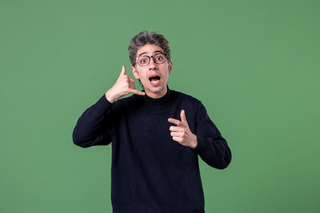 Ritratto di giovane genio vestito casualmente in studio shot che chiede di chiamare il muro verde