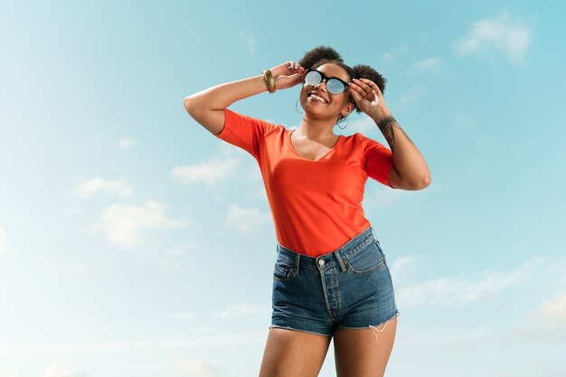 Ritratto di giovane modello di moda femminile su sfondo blu cielo.