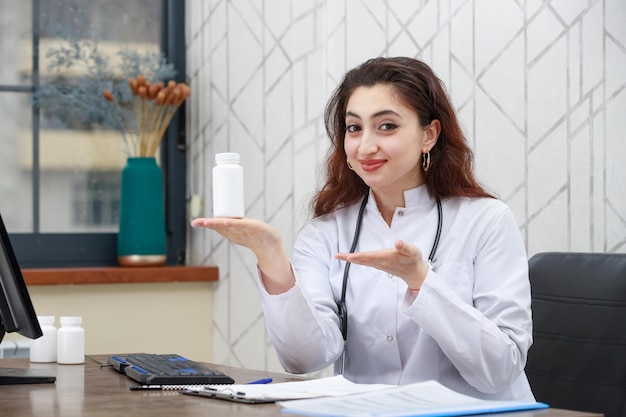 Ritratto di giovane operatore sanitario femminile che tiene la capsula del farmaco e punta la mano su di essa