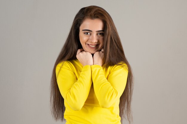 Ritratto di giovane ragazza in giallo in alto guardando e sorridente sul muro grigio.