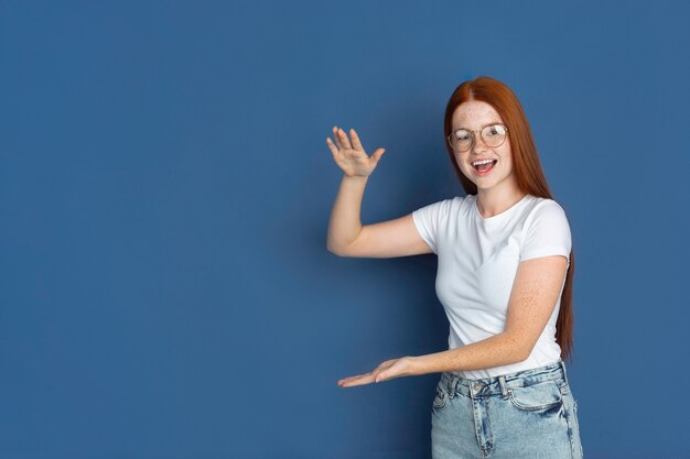 Ritratto di giovane ragazza isolato sulla parete blu dello studio