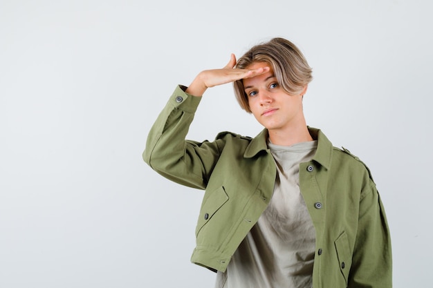 Ritratto di giovane ragazzo adolescente con la mano sopra la testa in giacca verde e guardando fiducioso vista frontale