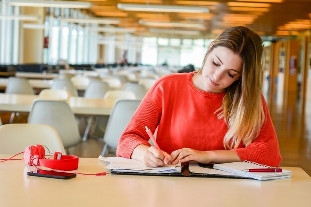 Ritratto di giovane studente che studia presso la biblioteca universitaria. Concetto di educazione e stile di vita.