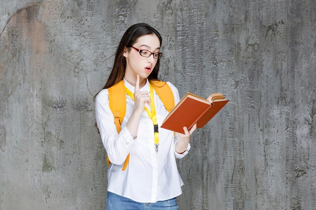 Ritratto di giovane studentessa in occhiali che legge il libro. Foto di alta qualità