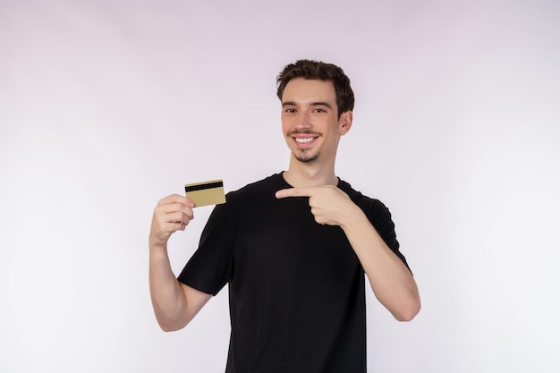 Ritratto di giovane uomo bello sorridente in abiti casual, mostrando carta di credito isolato su sfondo bianco