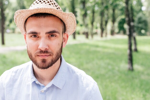 Ritratto di giovane uomo con la barba che indossa cappello al parco