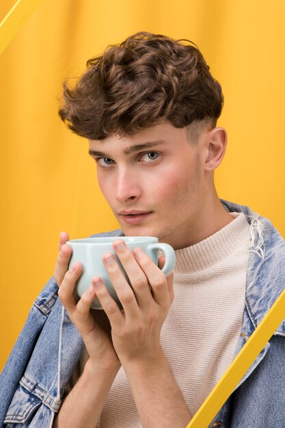 Ritratto di giovane uomo con tazza in una scena gialla