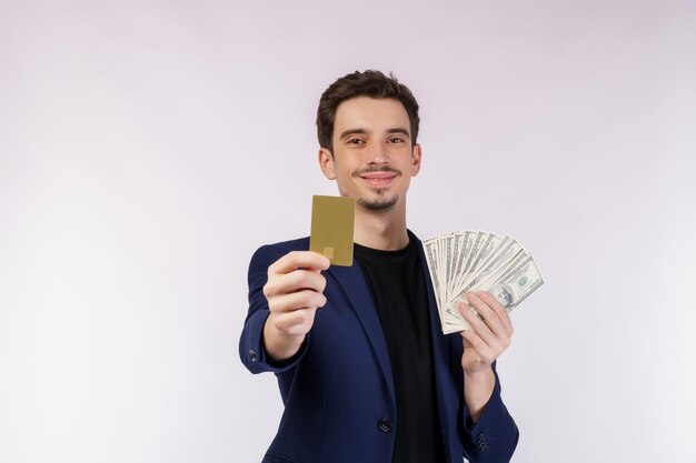 Ritratto di giovane uomo d'affari bello sorridente che mostra carta di credito e contanti isolati su sfondo bianco