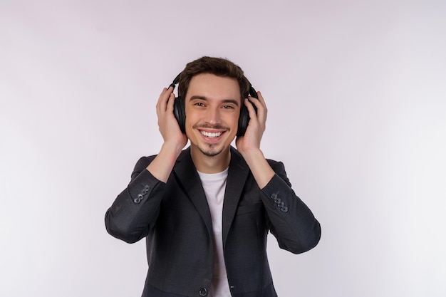 Ritratto di giovane uomo felice che indossa la cuffia e godetevi la musica su sfondo bianco