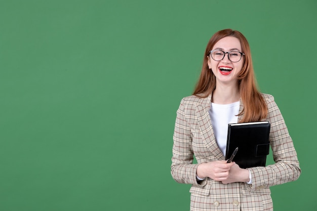 Ritratto di insegnante femminile che tiene il blocco note su green