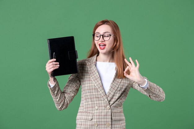 Ritratto di insegnante femminile che tiene il blocco note su green