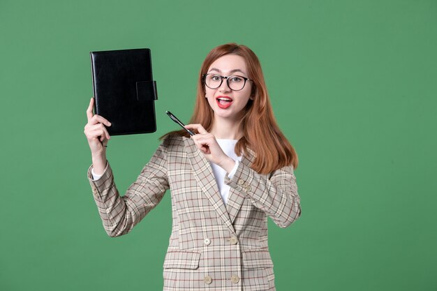 Ritratto di insegnante femminile che tiene il blocco note su green