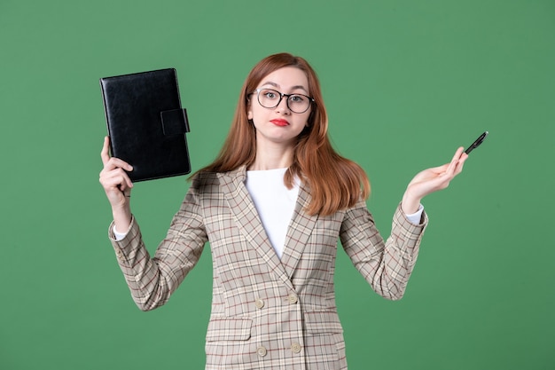 Ritratto di insegnante femminile che tiene il blocco note su green