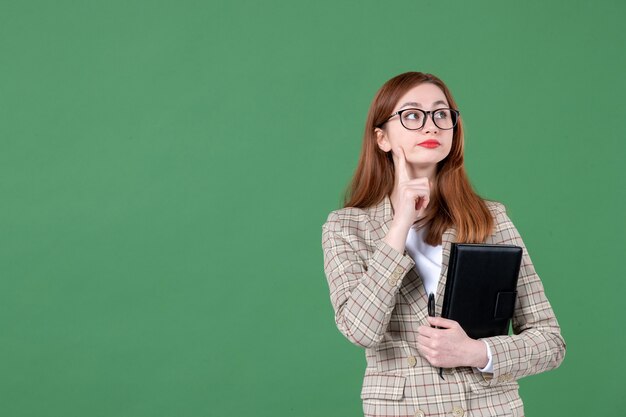 Ritratto di insegnante femminile con blocco note su green