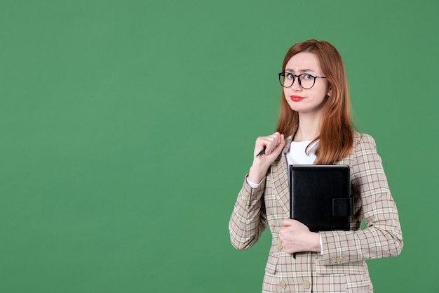 Ritratto di insegnante femminile con blocco note su green