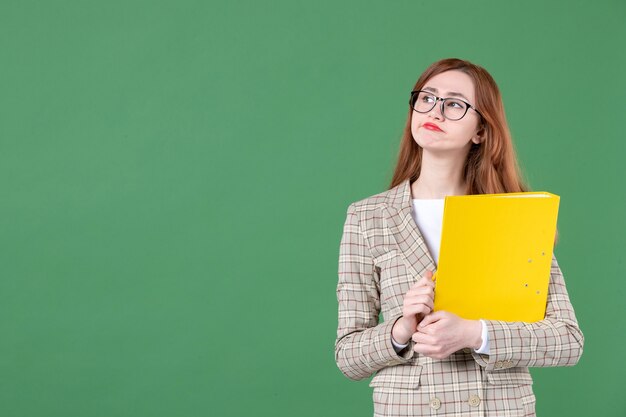 Ritratto di insegnante femminile in posa con file giallo e matita su green