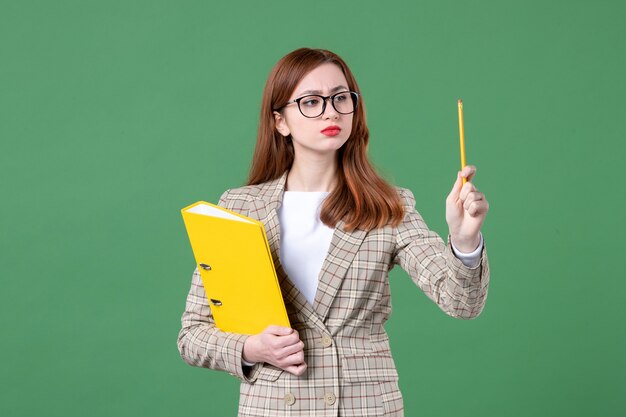 Ritratto di insegnante femminile in possesso di file gialli e matita su verde