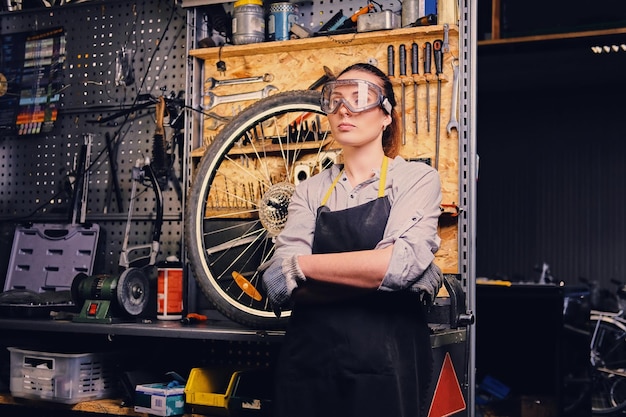 Ritratto di meccanico di biciclette femminile su sfondo supporto portautensili.