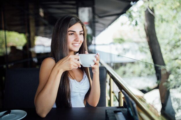 Ritratto di moda all'aperto di bella ragazza che beve tè e caffè