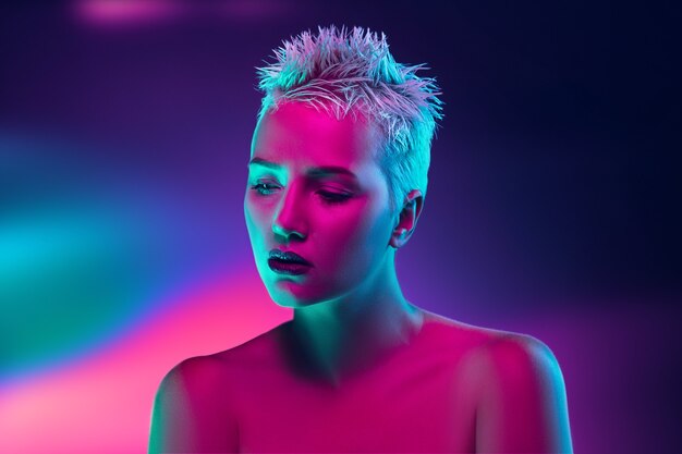 Ritratto di modella femminile in luce al neon su sfondo scuro studio.