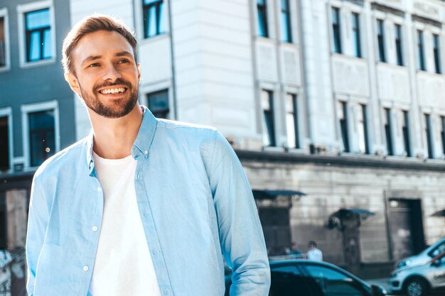 Ritratto di modello lambersexual bello fiducioso elegante hipster Uomo moderno vestito con camicia bianca Moda maschile in posa sullo sfondo della strada vicino ai grattacieli in occhiali da sole