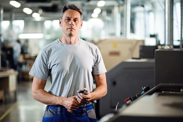 Ritratto di operatore di macchine CNC in piedi in una fabbrica e guardando la fotocamera