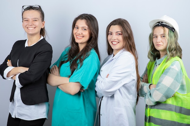 Ritratto di persone felici di diverse professioni in piedi con le braccia incrociate su sfondo bianco. Foto di alta qualità