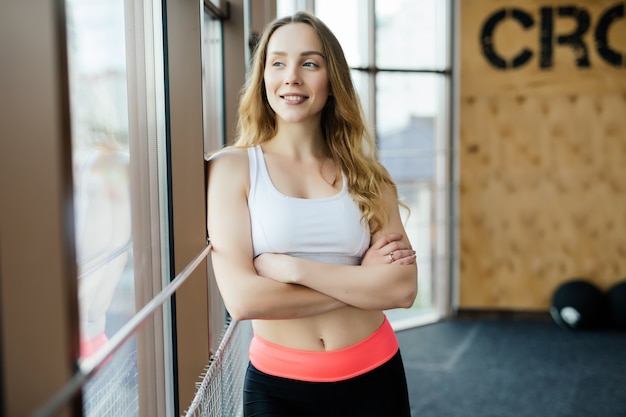 Ritratto di positività e ragazza che sorride alla macchina fotografica e posa con le braccia incrociate in palestra.