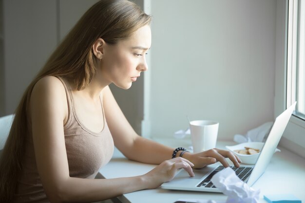 Ritratto di profilo di donna attraente che lavora su un computer portatile