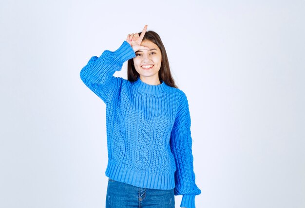 Ritratto di ragazza adolescente in maglione blu in piedi e sorridente felicemente.