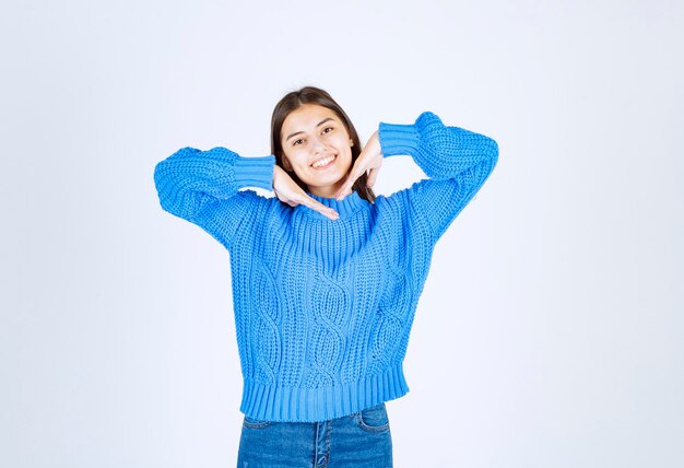 Ritratto di ragazza adolescente in maglione blu in piedi e sorridente felicemente.