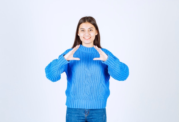 Ritratto di ragazza adorabile in maglione blu su bianco.