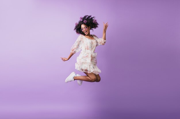 Ritratto di ragazza africana divertente in abbigliamento bianco che salta. allegra giovane donna bruna che esprime emozioni positive.