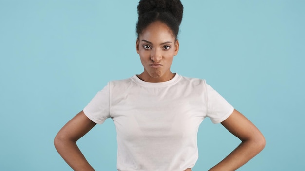 Ritratto di ragazza afroamericana seria arrabbiata che guarda in modo aggressivo a porte chiuse su sfondo colorato